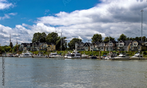 Small Village of new houses at the riverside of Fraser River, with marina for parking boats and yachts on the background of cloudy sky