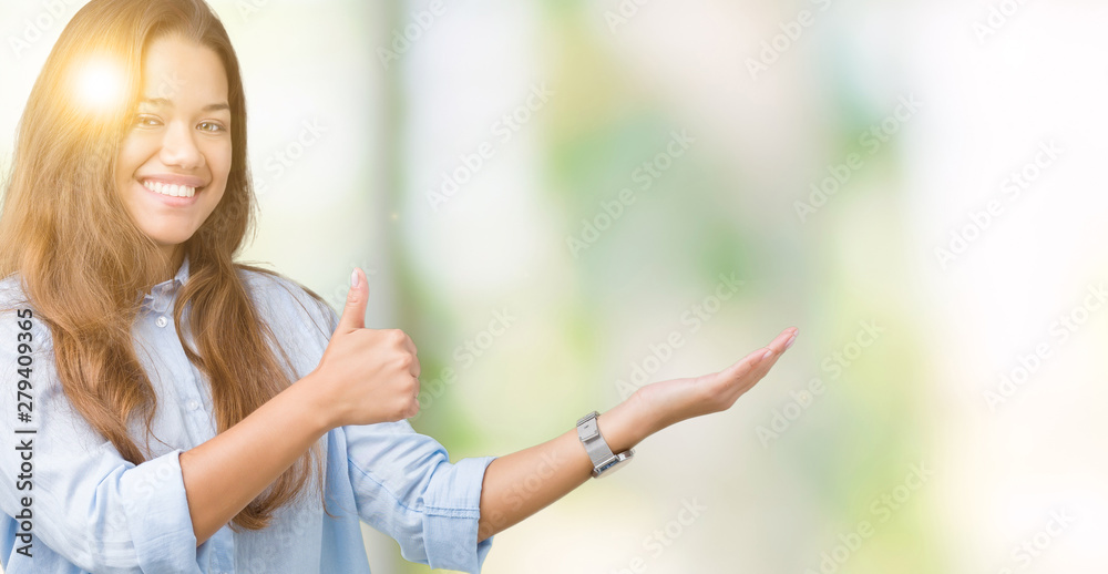 Young beautiful brunette business woman over isolated background Showing palm hand and doing ok gesture with thumbs up, smiling happy and cheerful Young beautiful brunette business woman over isolated background Showing palm hand and doing ok gesture with thumbs up, smiling happy and cheerful