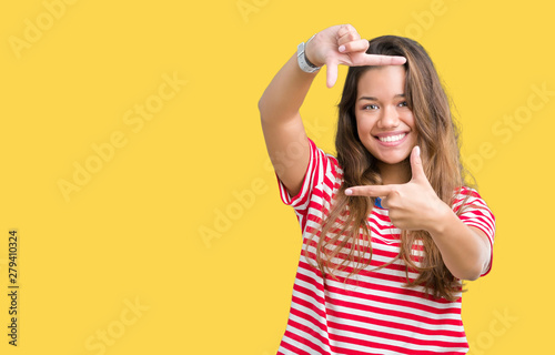 Young beautiful brunette woman wearing stripes t-shirt over isolated background smiling making frame with hands and fingers with happy face. Creativity and photography concept.