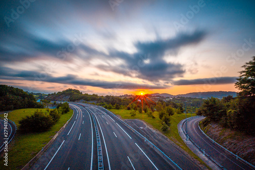 Long exposure in a sunset on a road, enter the clouds to cover the sun and take an orange color. Basque Country