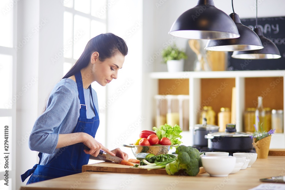 Young woman cutting vegetables in kitchen at home Young woman cutting vegetables in kitchen at home