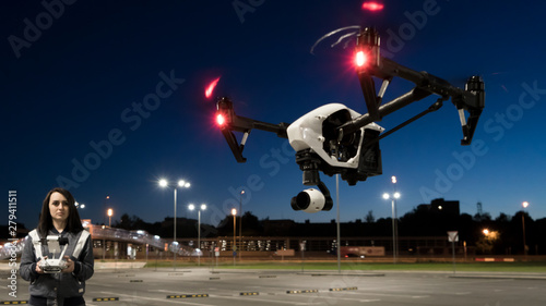 The girl controls the quadcopter. Drone in the night sky. The operator of the copter. The night sky and the lights. Flights on the quadrocopter.