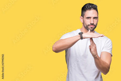 Handsome man wearing white t-shirt over yellow isolated background Doing time out gesture with hands, frustrated and serious face