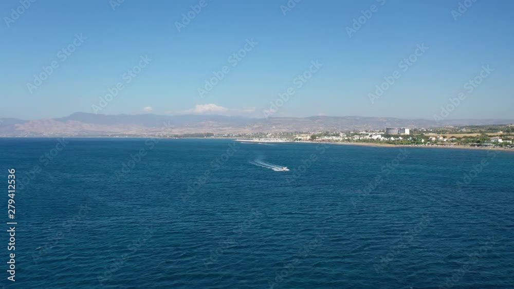 Aerial drone shot over the Mediterranean sea as a boat passes by the coast of Polis Chrysochou in Greece Aerial drone shot over the Mediterranean sea as a boat passes by the coast of Polis Chrysochou in Greece
