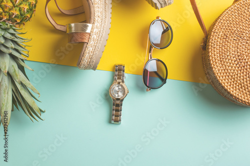 Summer colorful background with wicker fashion bag, tropical pineapple and women's shoes and sun glasses and watches. Summer fashion, the concept of the holiday.Flat lay.Yellow blue background.Banner photo