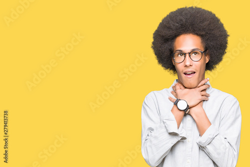 Young african american man with afro hair wearing glasses shouting and suffocate because painful strangle. Health problem. Asphyxiate and suicide concept.