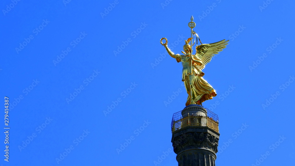 Fototapeta premium Lśniąca złota bogini zwycięstwa na Kolumnie Zwycięstwa w Berlinie na tle stalowego błękitnego nieba