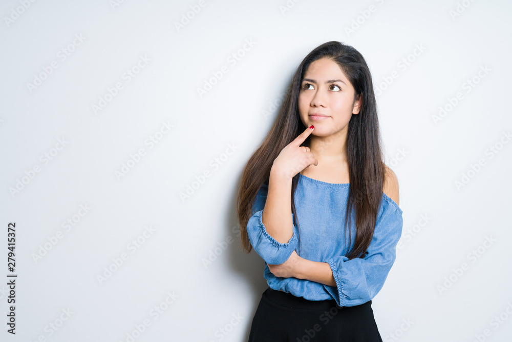 Beautiful brunette woman over isolated background with hand on chin thinking about question, pensive expression. Smiling with thoughtful face. Doubt concept. Beautiful brunette woman over isolated background with hand on chin thinking about question, pensive expression. Smiling with thoughtful face. Doubt concept.