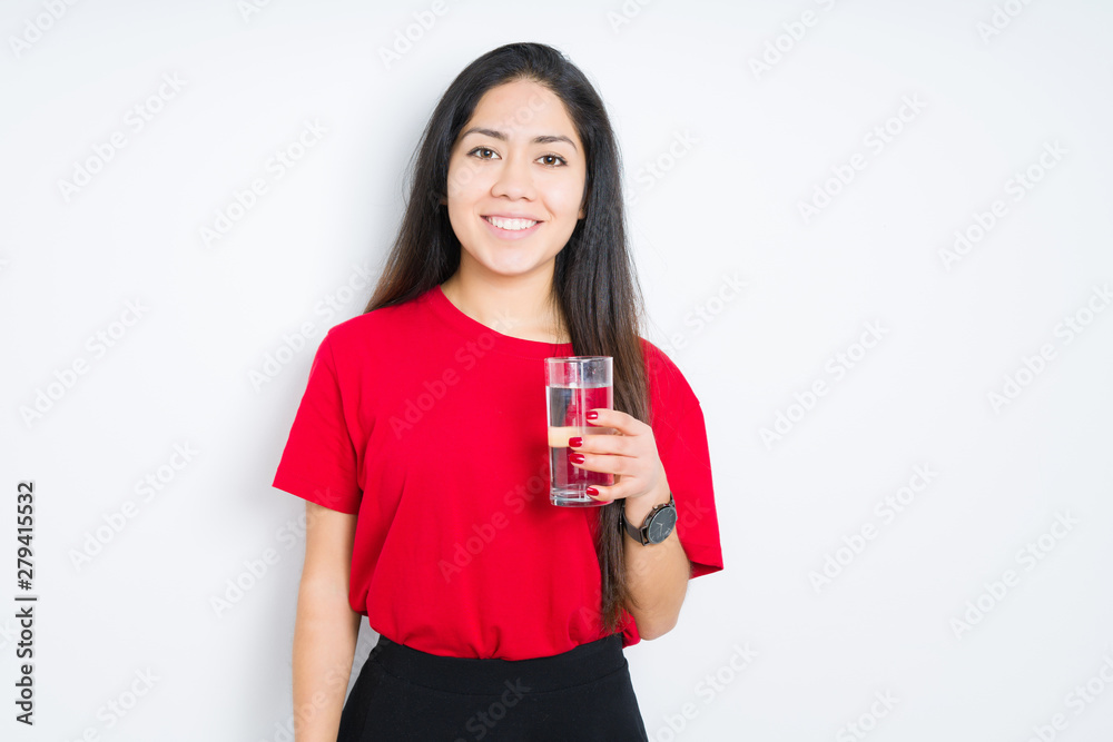 Young brunette woman drinking a glass of water over isolated background with a happy face standing and smiling with a confident smile showing teeth Young brunette woman drinking a glass of water over isolated background with a happy face standing and smiling with a confident smile showing teeth