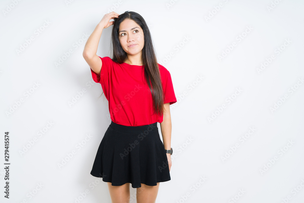 Beautiful brunette woman wearing red t-shirt and skirt over isolated background confuse and wonder about question. Uncertain with doubt, thinking with hand on head. Pensive concept. Beautiful brunette woman wearing red t-shirt and skirt over isolated background confuse and wonder about question. Uncertain with doubt, thinking with hand on head. Pensive concept.