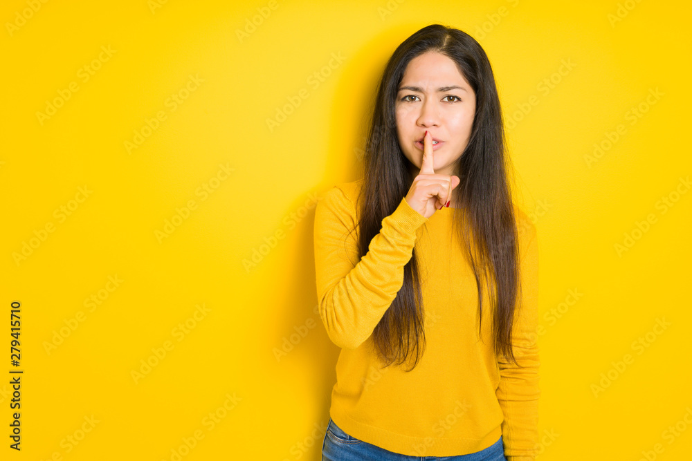 Beautiful brunette woman over yellow isolated background asking to be quiet with finger on lips. Silence and secret concept. Beautiful brunette woman over yellow isolated background asking to be quiet with finger on lips. Silence and secret concept.
