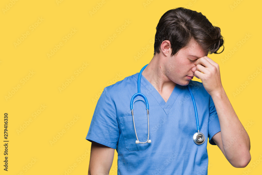 Young doctor wearing medical uniform over isolated background tired rubbing nose and eyes feeling fatigue and headache. Stress and frustration concept. Young doctor wearing medical uniform over isolated background tired rubbing nose and eyes feeling fatigue and headache. Stress and frustration concept.