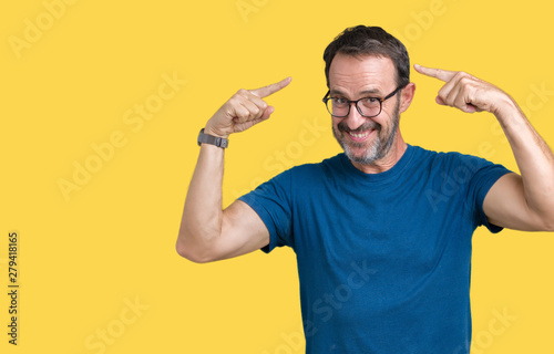 Handsome middle age hoary senior man wearin glasses over isolated background Smiling pointing to head with both hands finger, great idea or thought, good memory