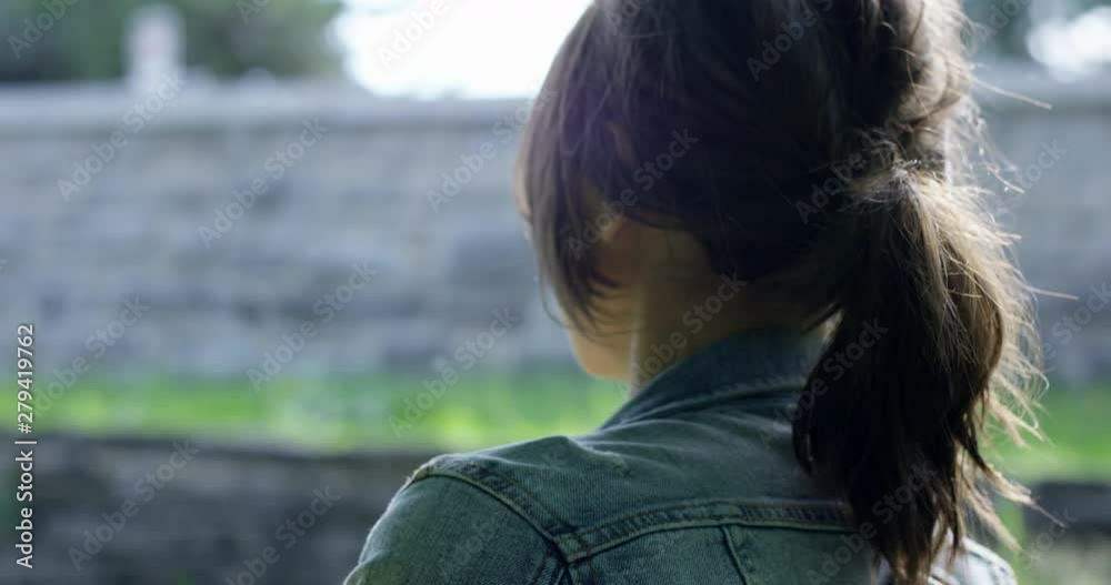 Stylish cool 20s woman walking through campus - close up from the side - hair shining in sunlight Stylish cool 20s woman walking through campus - close up from the side - hair shining in sunlight
