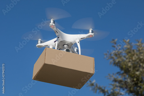 Unmanned Aircraft System (UAV) Quadcopter Drone Delivering Package