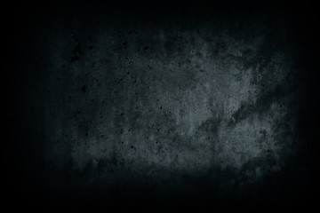 Dark black concrete wall from abandoned house dark alley with imperfections and natural cement texture with blue tones as scary surface background texture with dark vignetting.