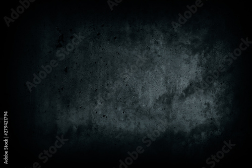 Dark black concrete wall from abandoned house dark alley with imperfections and natural cement texture with blue tones as scary surface background texture with dark vignetting.