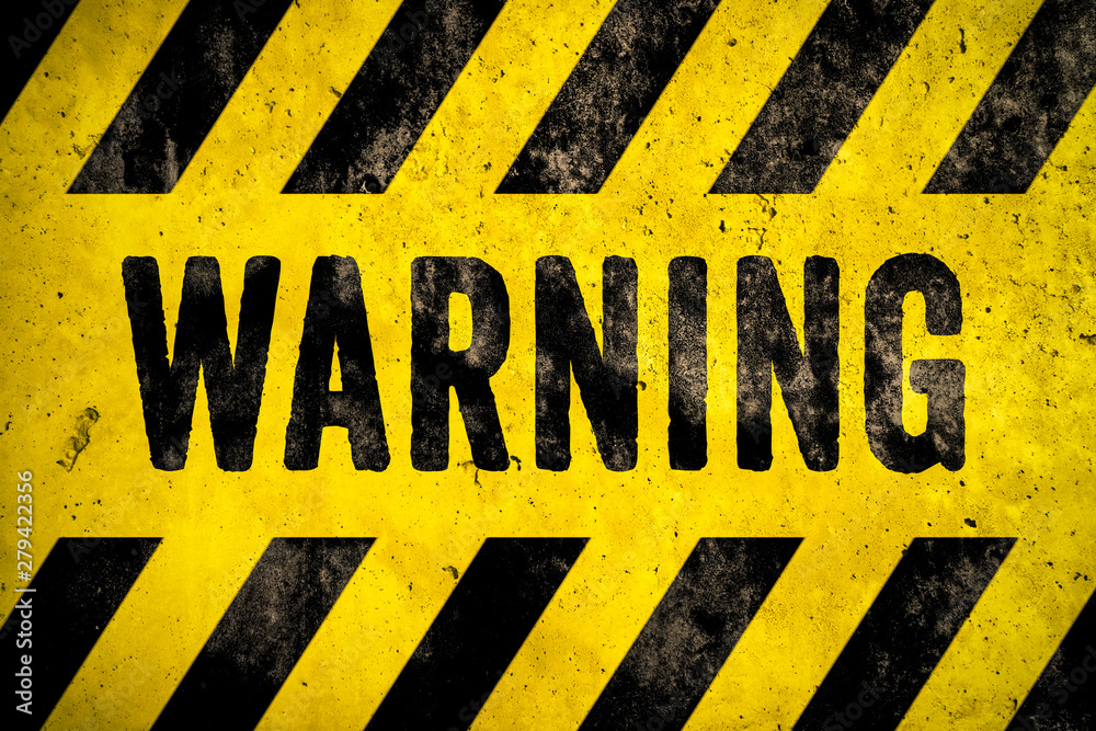 WARNING danger sign word text as stencil with yellow and black stripes painted over concrete