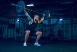 Young healthy man athlete doing exercise with the barbell in the gym. Single male model training hard and practicing in lunges. Concept of healthy lifestyle, sport, fitness, bodybuilding, crossfit.