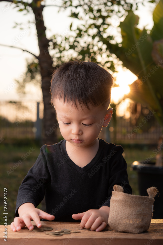 Cute Asian boy Counting money in the garden at home with sunset background. Cute Asian boy Counting money in the garden at home with sunset background.