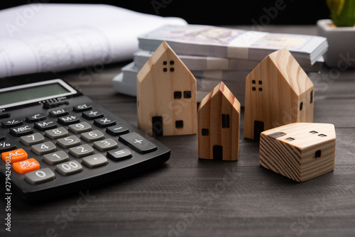 Small four wooden houses with modern design and calculator for home loans concept.