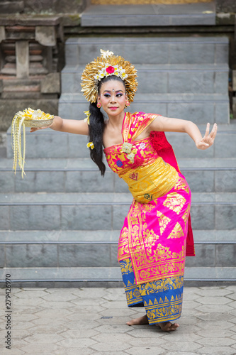 Female Pendet dancer carries flower petals