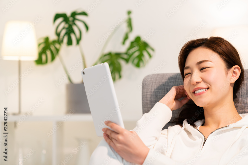 部屋でタブレットを見る女性