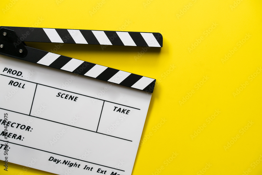 Φωτογραφία movie clapper on yellow table background ; film, cinema and video photography co