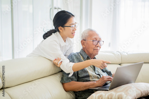 Woman teaching senior man to use a laptop