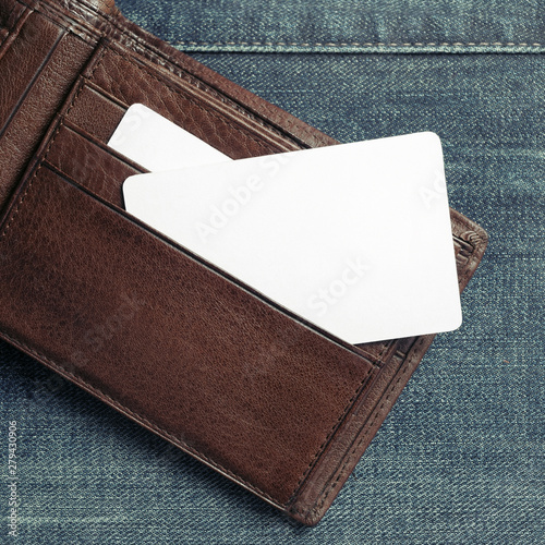 Blank business card or discount card in leather wallet on denim background. Copy space for text. Flat lay.