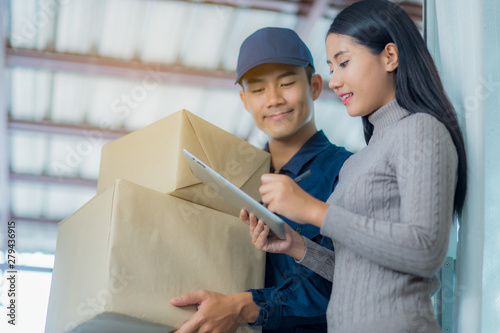 Woman customer signing receipt and receiving the parcel from delivery man. Business and logistic concept. photo