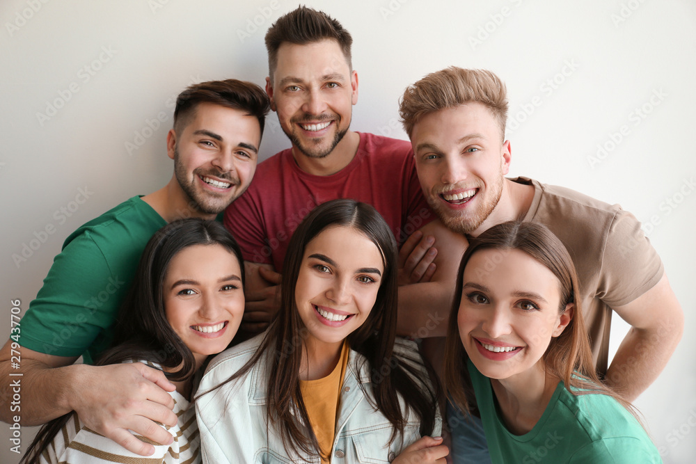 Group of happy people posing near light wall Group of happy people posing near light wall