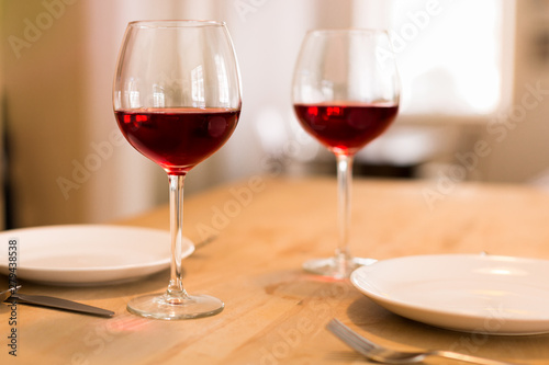 Romantic setting, two glasses of red wine on a dinner table.