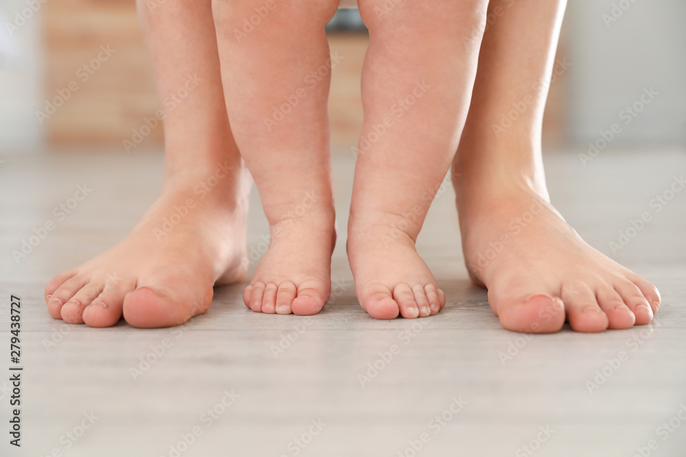 Mother and her baby standing on floor, closeup of legs Mother and her baby standing on floor, closeup of legs