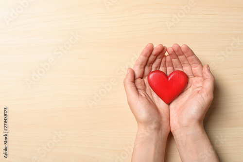 Woman holding heart on wooden background  top view with space for text. Donation concept