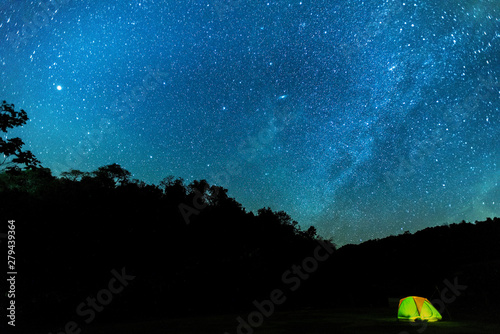 Tourist summer camping at night on the  mountain.A tent glows under a night sky full of stars. A wonderful night.
