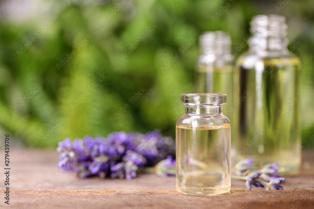 Bottles with natural lavender essential oil on wooden table against blurred background. Space for text Bottles with natural lavender essential oil on wooden table against blurred background. Space for text