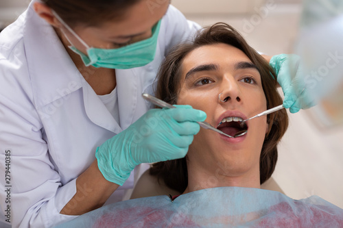 Dark-haired good-looking teen lying in a dentists chair