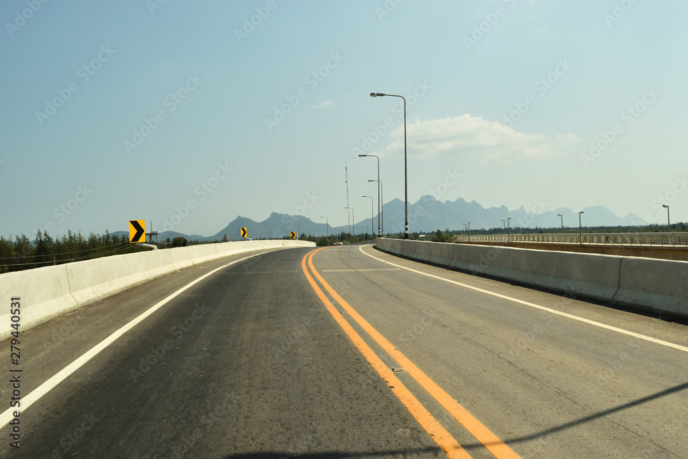 Open road on the bridge with mountain and blue sky in background, Southeast Asia, Thailand