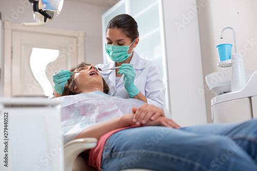 Focused professional female doctor checking patients dental health