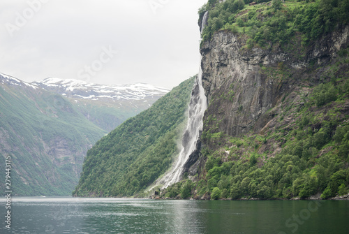 Geirangerfjord seen from the sea safari ride. Waterfalls, mountains, peaceful water of the bay which reflects the falls. Unforgettable UNESCO World Heritage Site in Scandinavia, Norway.