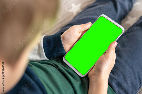 Phone a for keying is holding kid. Smartphone with a hromakey in the hands of a child.Smartphone with a green screen in hand child . top view close up photo