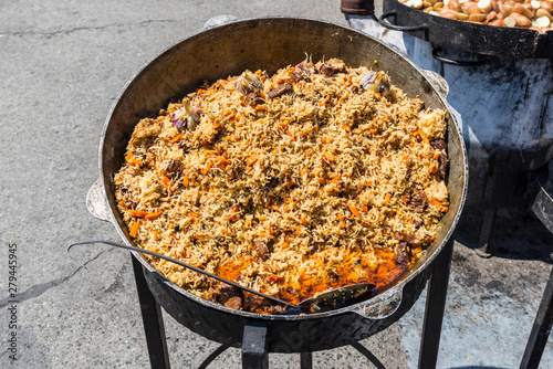 Traditional dish of oriental cuisine - pilaf with meat in a larger vat on the street during the festival
