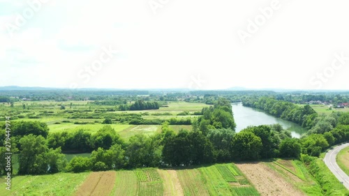 Rural countryside landscape in Croatia, Kupa river meandering between agriculture fields, panoramic view from drone, reveal shot photo