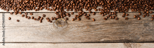 Overhead shot of roasted coffee beans on wooden background.