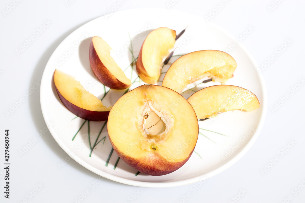 Slices of peach on a plate in a white background