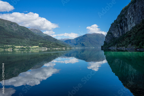 Panoramic view of The Sognefjord (Sognefjorden), nicknamed the King of the Fjords. Te largest and deepest fjord in Norway. Symmetry created by reflections in the still ocean water. Bright midsummer.