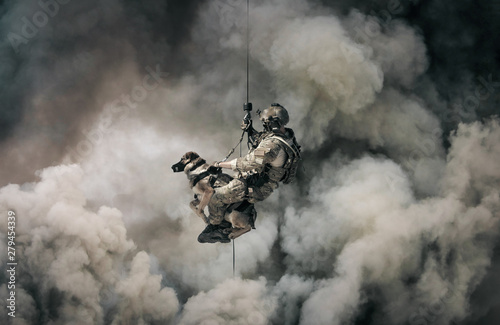 Military soldier with dog roping helicopter between mist and smoke