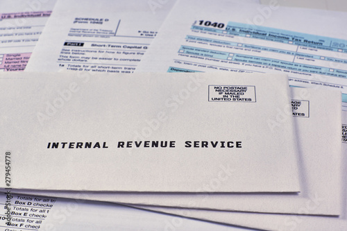 Three mails from the Internal Revenue Service lie on 1040, Schedule D form 1040 and 1040a tax forms