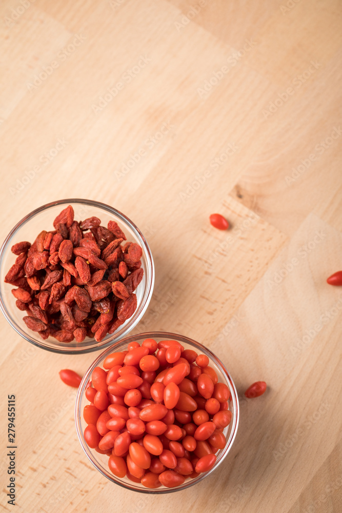 Frische und getrocknete Goji-Beeren Superfood in Glas Schale auf Holz Brett Hintergrund Frische und getrocknete Goji-Beeren Superfood in Glas Schale auf Holz Brett Hintergrund